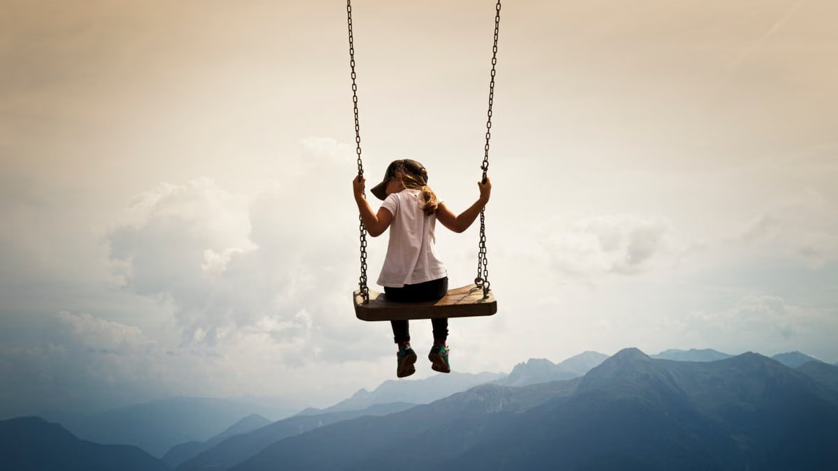 A girl swings high above the picturesque mountains of Vipiteno, Italy, embracing freedom and nature.
